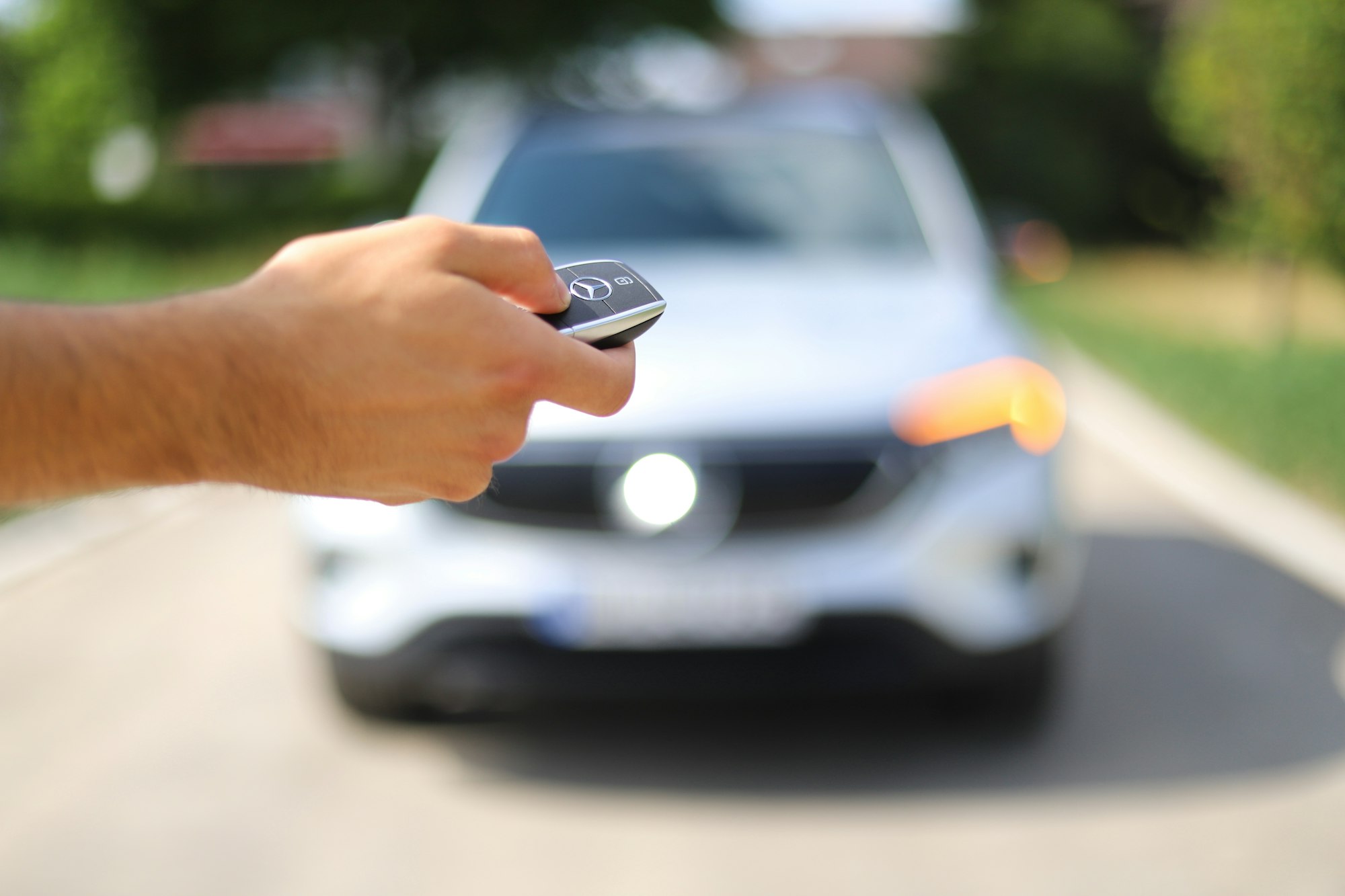 Driver pointing a car key fob at a parked SUV
